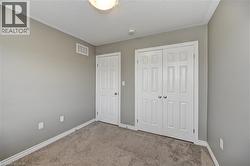Neutral-toned walls with carpet flooring, featuring a paneled door and bi-fold closet doors - 