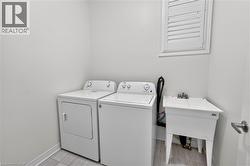 Dedicated utility area featuring a window with white shutters, a laundry sink, and light-toned tile flooring - 