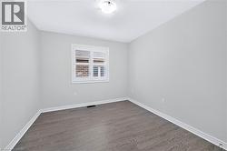 Room featuring light gray walls, wood-finish flooring, and white baseboards - 