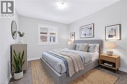 Light-filled bedroom featuring white walls, wood-finish flooring, and a window with white louvered blinds - 