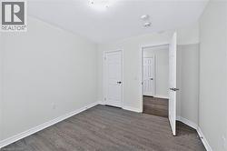Interior room featuring wood-finish flooring, white baseboards, and light-toned walls - 
