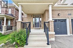 Brick exterior with stone accents, covered front porch, and concrete steps with black metal railings - 