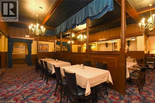 Elegant dining space featuring rich wood paneling, crystal chandeliers, and deep jewel-toned patterned flooring - 942-946 Barton Street E, Hamilton, ON 