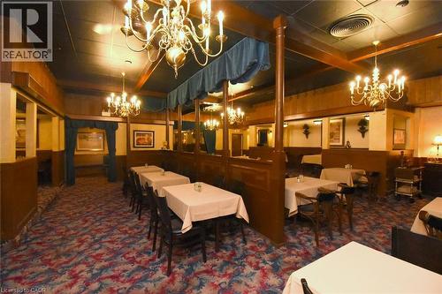 Elegant dining space featuring wood-paneled walls, ornate crystal chandeliers, and a patterned area rug - 942-946 Barton Street E, Hamilton, ON 
