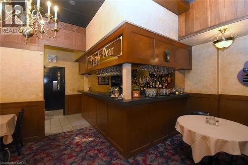 Classic wood-paneled bar featuring a full liquor display, brass chandeliers, and professional-grade bar counter with integrated shelving - 942-946 Barton Street E, Hamilton, ON 