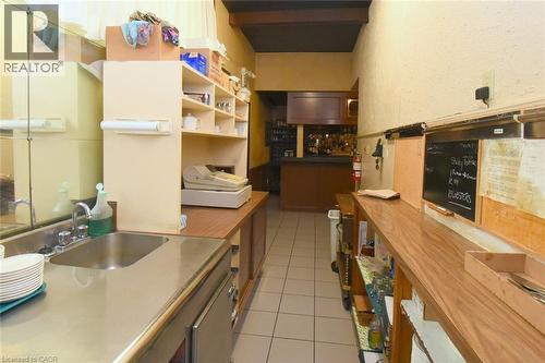 Galley-style kitchen featuring stainless steel countertops, tile flooring, open shelving with wood-finish cabinetry, and ample storage with upper and lower cabinet systems - 942-946 Barton Street E, Hamilton, ON 