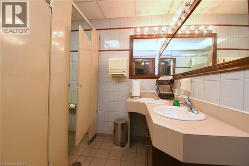 Modern bathroom featuring a curved vanity with an integrated sink, polished countertop surface, and contemporary wall-mounted faucet - 942-946 Barton Street E, Hamilton, ON 