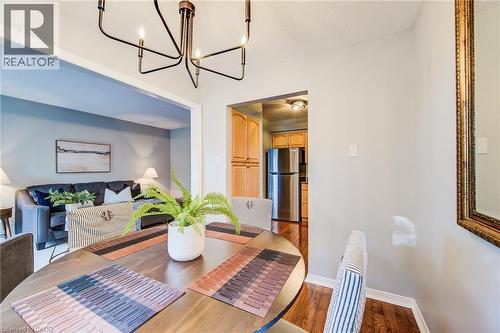 Dining area featuring a contemporary chandelier, wood-finish flooring, and a decorative framed mirror - 360 Cornridge Place Unit# 2, Waterloo, ON 