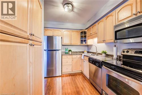 Kitchen featuring wood-finish flooring, light wood cabinetry, stainless steel appliances, and dark stone countertops - 360 Cornridge Place Unit# 2, Waterloo, ON 