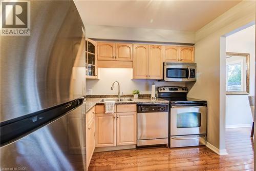 Kitchen featuring wood-finish flooring, light wood cabinetry, stone countertops, and stainless steel appliances - 360 Cornridge Place Unit# 2, Waterloo, ON 