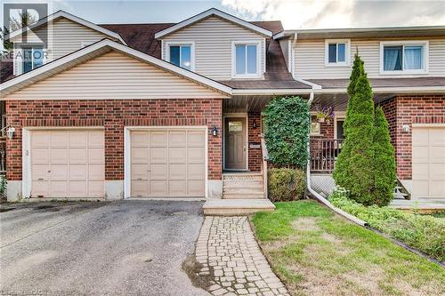Brick and siding exterior with a pitched roofline, featuring two attached garage doors, a stone walkway, and established landscaping - 360 Cornridge Place Unit# 2, Waterloo, ON 