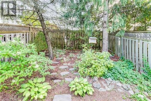 Fenced yard with mature trees, established plantings, and stone pavers - 360 Cornridge Place Unit# 2, Waterloo, ON 