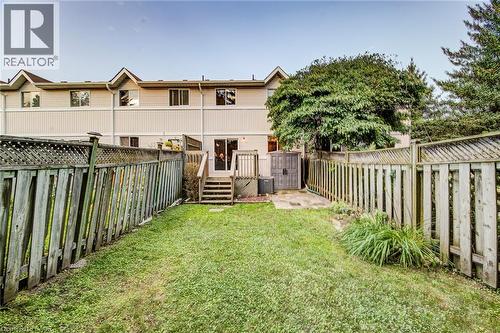 Rear yard featuring a grass lawn, privacy fencing, and mature trees - 360 Cornridge Place Unit# 2, Waterloo, ON 
