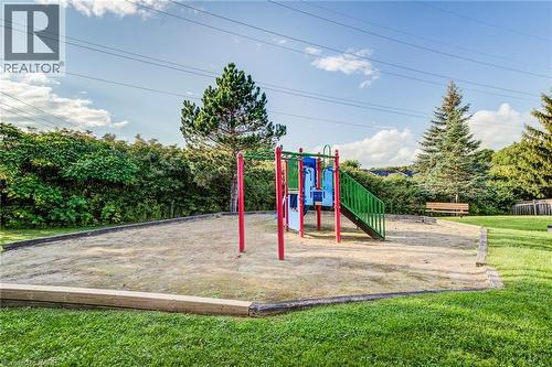 Recreational play structure with slide and climbing features, set within a sand-filled area, surrounded by a manicured lawn - 360 Cornridge Place Unit# 2, Waterloo, ON 