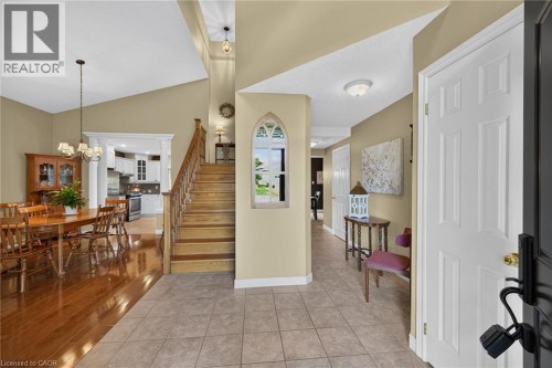 Vaulted ceiling, wood-finish flooring, wood staircase with railing, recessed kitchen archway, and tiled entry - 10 Balvenie Boulevard, Caledonia, ON 