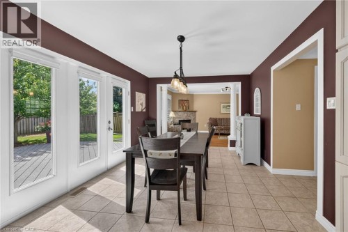 Tile flooring with a dark wood-finish dining table, double French doors, and a deck - 10 Balvenie Boulevard, Caledonia, ON 