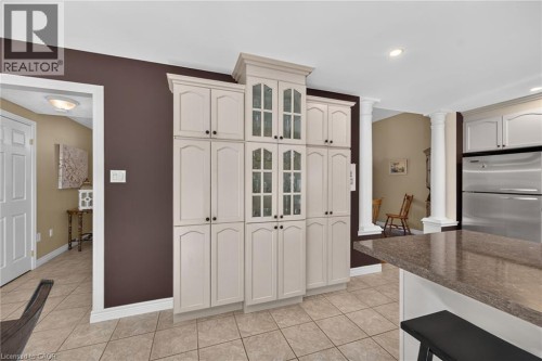 Floor-to-ceiling cabinetry with glass panel accents, tile flooring, recessed lighting, and a kitchen island with a stone-finish countertop - 10 Balvenie Boulevard, Caledonia, ON 