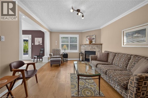 Hardwood-finish flooring, stone-clad fireplace, crown molding, track lighting, and a white-framed window - 10 Balvenie Boulevard, Caledonia, ON 
