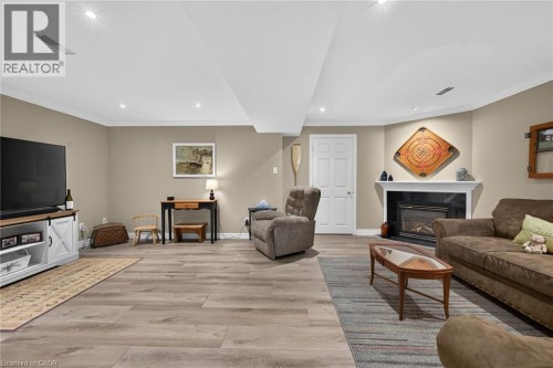 Recessed ceiling lights, wood-finish flooring, neutral wall paint, white trim, and a fireplace with a mantel - 10 Balvenie Boulevard, Caledonia, ON 