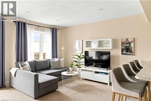 Recessed ceiling lighting, a large window with white sheers, built-in display cabinetry, and a light-toned carpet - 187 Eden Oak Trail, Kitchener, ON 