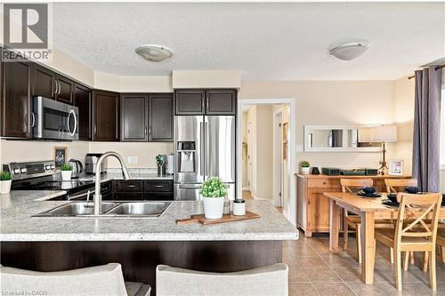 Kitchen with dark wood-finish cabinetry, stainless steel appliances, and a double basin sink - 187 Eden Oak Trail, Kitchener, ON 