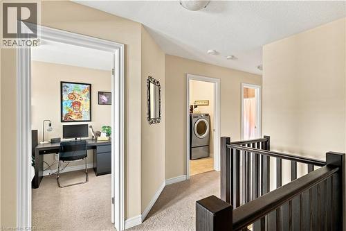Hallway with neutral wall color, carpeted flooring, and dark-stained wooden railings - 187 Eden Oak Trail, Kitchener, ON 
