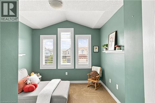 Serene bedroom retreat showcasing soft sage-green walls, white vaulted ceiling with recessed lighting, and triple casement windows with plantation shutters framing natural light - 187 Eden Oak Trail, Kitchener, ON 
