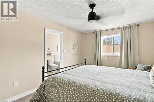 Room with a ceiling fan with integrated lighting, a window, and an open doorway leading to a bathroom with a toilet and built-in shelving - 187 Eden Oak Trail, Kitchener, ON 