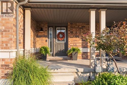 Brick exterior featuring a covered porch, support columns, and a dark entry door with a sidelight - 187 Eden Oak Trail, Kitchener, ON 