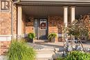 Brick exterior featuring a covered porch, support columns, and a dark entry door with a sidelight - 187 Eden Oak Trail, Kitchener, ON 