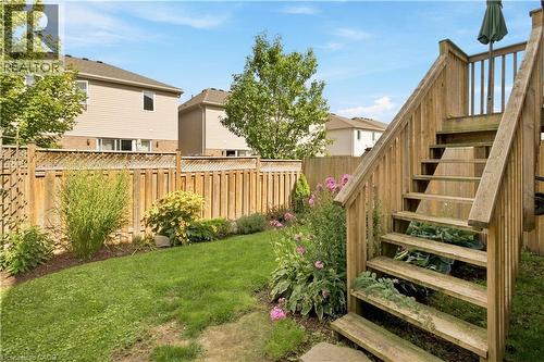 Expansive green space featuring a wooden privacy fence, mature trees, and a multi-level wooden deck with stairs - 187 Eden Oak Trail, Kitchener, ON 