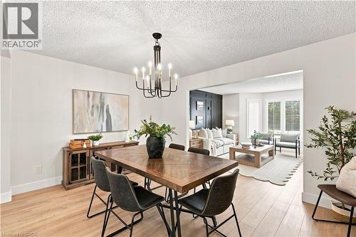 Dining area with wood-finish flooring, a contemporary chandelier, and a built-in wood-finish sideboard - 62 Corfield Drive, Kitchener, ON 