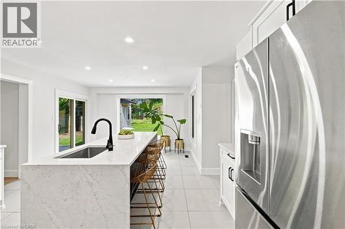 Kitchen island with a waterfall-edge countertop, undermount sink, and matte black faucet - 62 Corfield Drive, Kitchener, ON 
