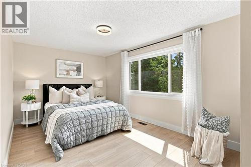 Light wood-finish flooring, a contemporary ceiling light fixture, and a large window with white trim - 62 Corfield Drive, Kitchener, ON 