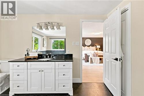 White vanity with extensive storage, dark countertop, and a large wall-mounted mirror - 62 Corfield Drive, Kitchener, ON 