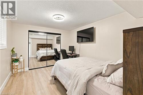 Light wood-finish flooring, a contemporary flush-mount ceiling light, and a wall-mounted television - 62 Corfield Drive, Kitchener, ON 