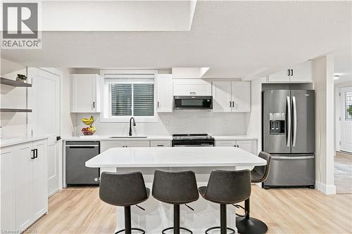White cabinetry, stainless steel appliances, wood-finish flooring, white countertops, and a central island - 62 Corfield Drive, Kitchener, ON 