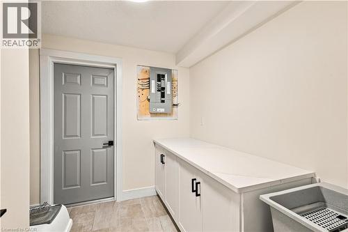White cabinetry with matte black hardware, light-toned countertop, and a utility sink - 62 Corfield Drive, Kitchener, ON 