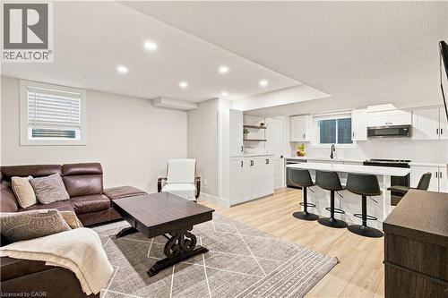 Recessed lighting illuminating a modern kitchen featuring white cabinetry, a built-in microwave, and a breakfast bar with seating - 62 Corfield Drive, Kitchener, ON 