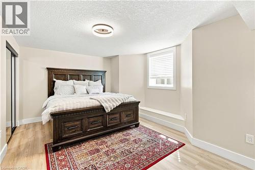 Wood-finish flooring, built-in window seat, window with blinds, recessed lighting, and mirrored closet doors - 62 Corfield Drive, Kitchener, ON 