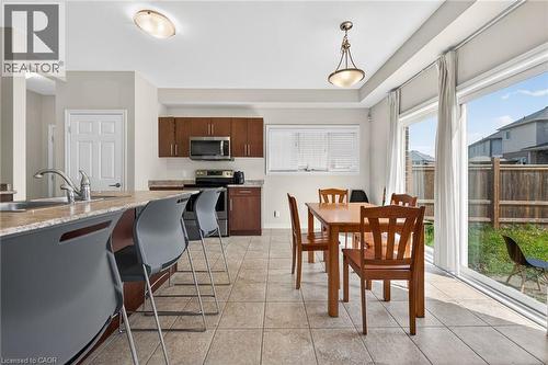 Kitchen featuring wood-finish cabinetry, stainless steel appliances, and a breakfast bar with a sink - 9 Winterberry Boulevard, Thorold, ON 