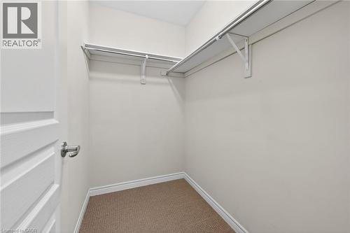Closet featuring carpet flooring, built-in shelving, and hanging rods - 9 Winterberry Boulevard, Thorold, ON 