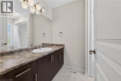 Bathroom featuring a single vanity with dark wood-finish cabinetry, a white oval sink, and a marbled countertop - 9 Winterberry Boulevard, Thorold, ON 