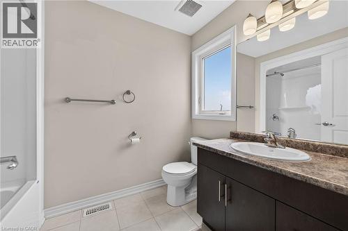 Bathroom featuring a white bathtub, a single vanity with a dark wood-finish cabinet, a light-toned countertop, a rectangular mirror, and a window - 9 Winterberry Boulevard, Thorold, ON 