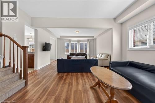 Wood-finish flooring throughout, curved wooden staircase with carpeted treads, and multiple windows providing natural light - 9 Winterberry Boulevard, Thorold, ON 
