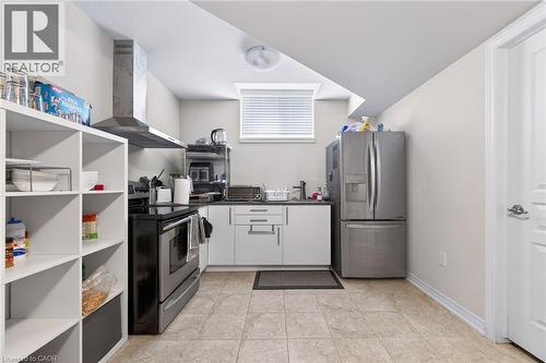 Tiled flooring, stainless steel appliances, white cabinetry, integrated range hood, and a built-in shelving unit - 9 Winterberry Boulevard, Thorold, ON 