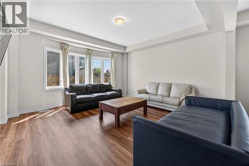 Spacious living area featuring wood-finish flooring, a tray ceiling, and a large multi-pane window - 9 Winterberry Boulevard, Thorold, ON 