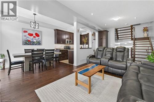 Open-concept living area with dark wood-finish flooring, recessed lighting, and a contemporary chandelier - 88 Highgate Drive, Hamilton, ON 