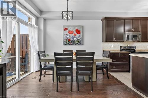 Open-concept space featuring wood-finish flooring, a sliding glass door for outdoor access, dark wood cabinetry, and a built-in stainless steel microwave - 88 Highgate Drive, Hamilton, ON 