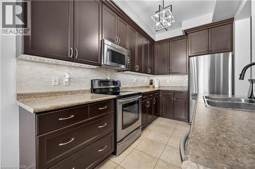 Kitchen with dark wood cabinetry, light-toned countertops, and a tile backsplash - 88 Highgate Drive, Hamilton, ON 